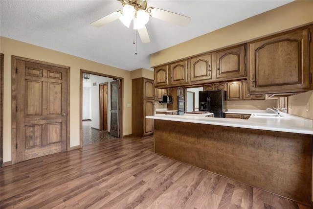 4633 Northwood Dr NE, Cedar Rapids, IA 52402 - kitchen featuring black appliances, a sink, a peninsula, wood finished floors, and light countertops