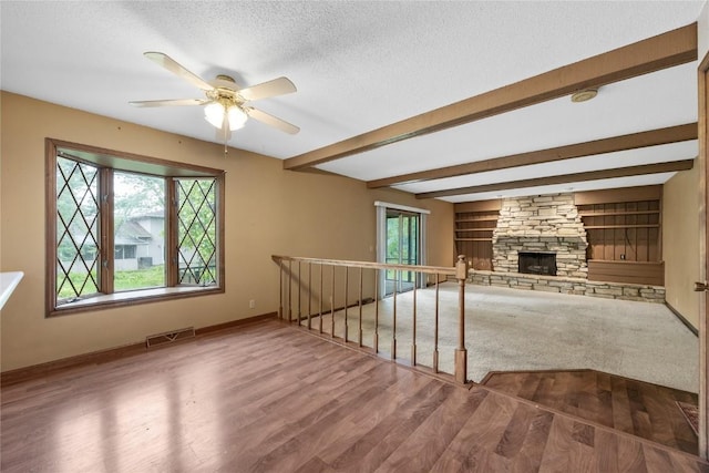4633 Northwood Dr NE, Cedar Rapids, IA 52402 - unfurnished living room with a ceiling fan, a textured ceiling, baseboards, wood finished floors, and a stone fireplace