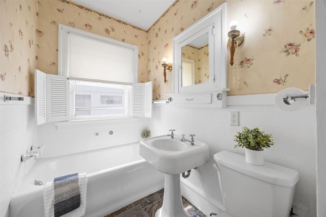 2251 Bever Ave SE, Cedar Rapids, IA 52403 - full bathroom featuring wallpapered walls, toilet, a bath, and a wainscoted wall
