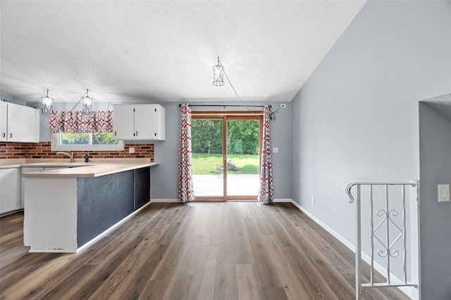 607 E 6th St, Tipton, IA 52772 - kitchen with white cabinets, wood finished floors, light countertops, tasteful backsplash, and a textured ceiling