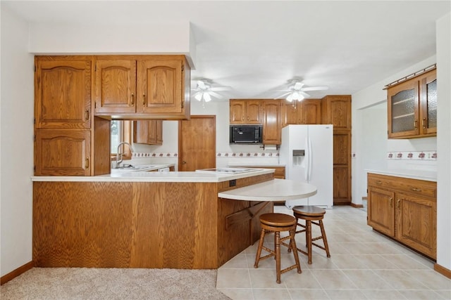 6405 Hillcrest Rd, Cedar Rapids, IA 52404 - kitchen featuring white appliances, a sink, a peninsula, a ceiling fan, and brown cabinetry