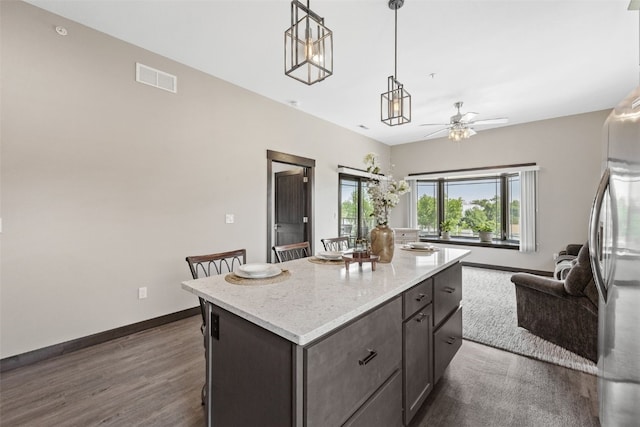 1871 Ellis Blvd NW Unit 309, Cedar Rapids, IA 52405 - kitchen with open floor plan, a center island, a ceiling fan, freestanding refrigerator, and baseboards