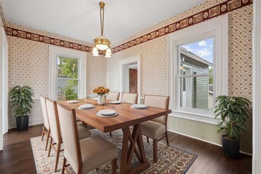 611 3rd Ave NE, Independence, IA 50644 - dining space with wallpapered walls, baseboards, and dark wood-style floors