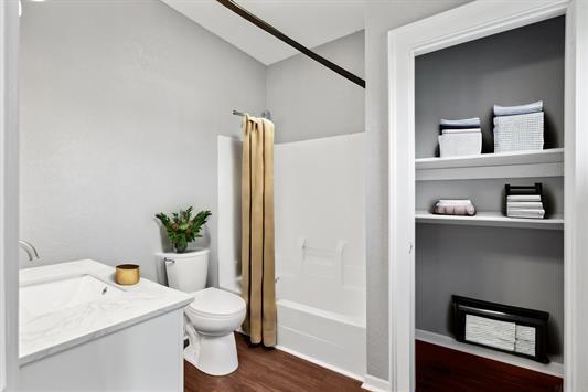 611 3rd Ave NE, Independence, IA 50644 - bathroom featuring toilet, wood finished floors, vanity, and bathing tub / shower combination