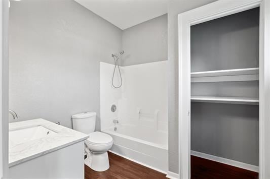 611 3rd Ave NE, Independence, IA 50644 - full bathroom featuring toilet, shower / bathtub combination, vanity, and wood finished floors