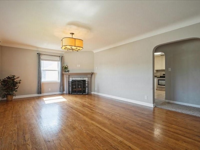 751 30th St NE, Cedar Rapids, IA 52402 - unfurnished living room featuring arched walkways, wood finished floors, a fireplace, and baseboards
