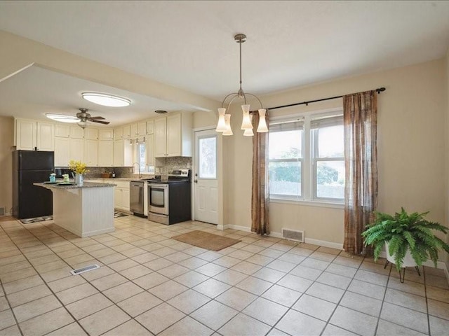 751 30th St NE, Cedar Rapids, IA 52402 - kitchen with stainless steel appliances, tasteful backsplash, light tile patterned floors, a center island, and baseboards