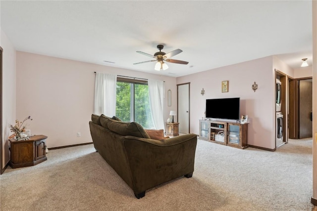 1015 Woodland Heights Ct SE Unit 14, Cedar Rapids, IA 52403 - living room featuring stacked washer and clothes dryer, light carpet, ceiling fan, and baseboards