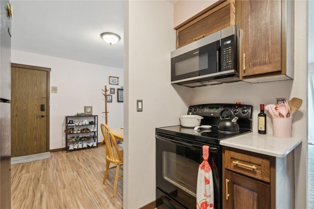 1015 Woodland Heights Ct SE Unit 14, Cedar Rapids, IA 52403 - kitchen with black electric range, stainless steel microwave, light wood-style flooring, light countertops, and baseboards