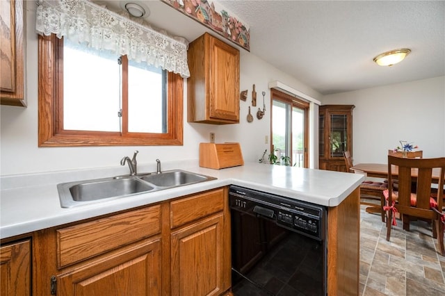 109 Oreole NE, Solon, IA 52333 - kitchen featuring dishwasher, a sink, brown cabinetry, a peninsula, and light countertops