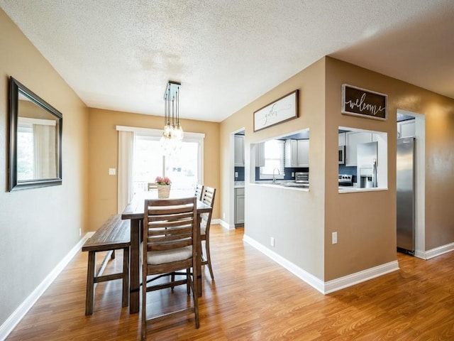 4721 Pine View Dr NE, Cedar Rapids, IA 52402 - dining room with light wood-style flooring, a textured ceiling, a chandelier, and baseboards