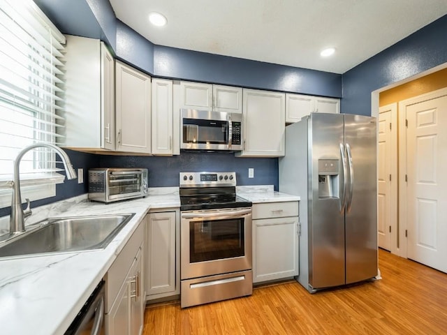 4721 Pine View Dr NE, Cedar Rapids, IA 52402 - kitchen featuring appliances with stainless steel finishes, a sink, light wood-type flooring, and light stone counters
