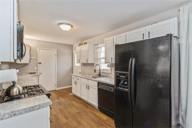 281 NW Jacolyn Dr, Cedar Rapids, IA 52405 - kitchen featuring black appliances, a sink, light countertops, white cabinetry, and light wood finished floors