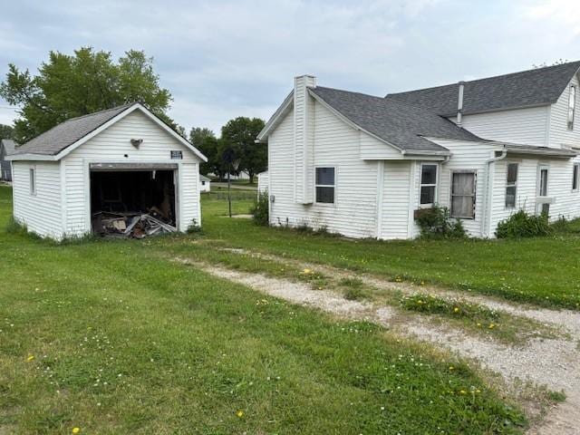4 E Wood St, Urbana, IA 52345 - view of property exterior featuring a garage, a chimney, an outdoor structure, a yard, and a shingled roof
