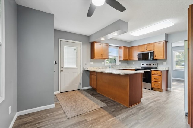 1626 High View Dr, Mount Vernon, IA 52314 - kitchen with appliances with stainless steel finishes, baseboards, light wood finished floors, a peninsula, and a ceiling fan