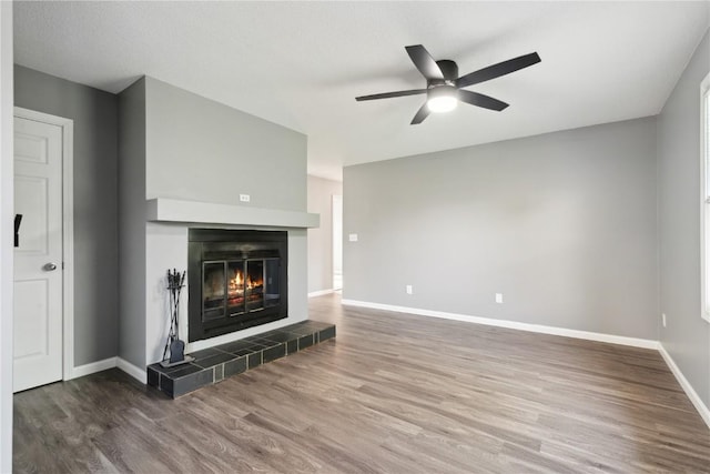 1626 High View Dr, Mount Vernon, IA 52314 - unfurnished living room featuring wood finished floors, a ceiling fan, baseboards, and a tile fireplace