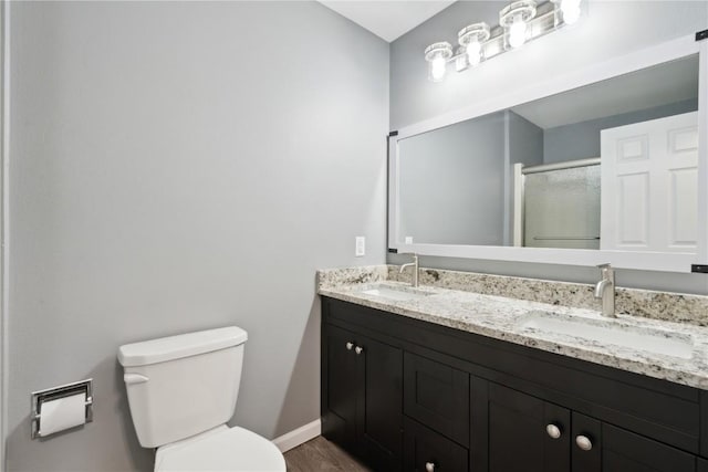 1626 High View Dr, Mount Vernon, IA 52314 - full bathroom featuring double vanity, baseboards, toilet, an enclosed shower, and wood finished floors