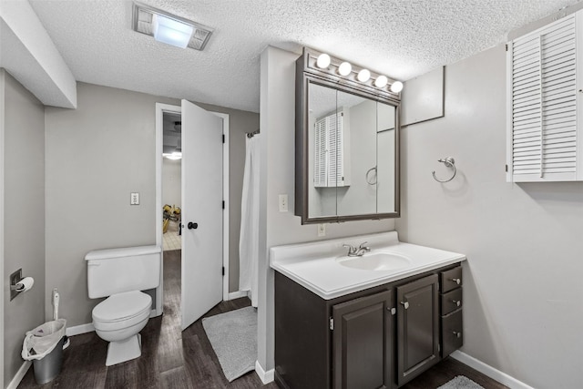2043 Brookland Dr NE, Cedar Rapids, IA 52402 - bathroom with vanity, toilet, wood finished floors, baseboards, and a textured ceiling