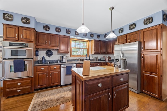 3009 Terry Dr SE, Cedar Rapids, IA 52403 - kitchen with stainless steel appliances, light wood-style floors, a center island, pendant lighting, and decorative backsplash