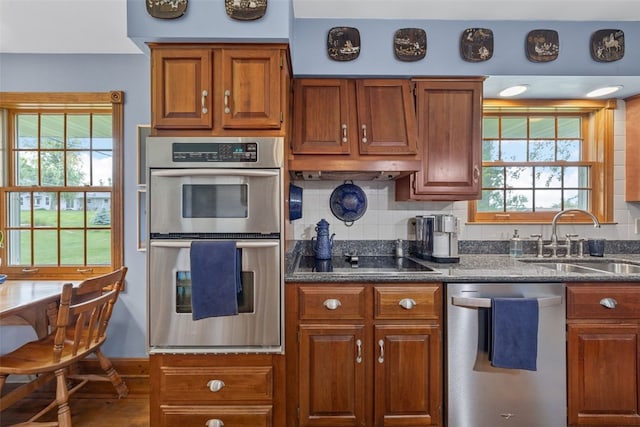 3009 Terry Dr SE, Cedar Rapids, IA 52403 - kitchen with stainless steel appliances, a sink, plenty of natural light, and brown cabinetry