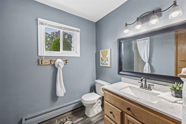 1920 26th St, Marion, IA 52302 - bathroom with a baseboard heating unit, toilet, vanity, and wood finished floors