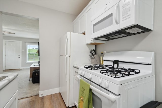 944 L St SW, Cedar Rapids, IA 52404 - kitchen with white appliances, white cabinetry, light wood-style flooring, and baseboards