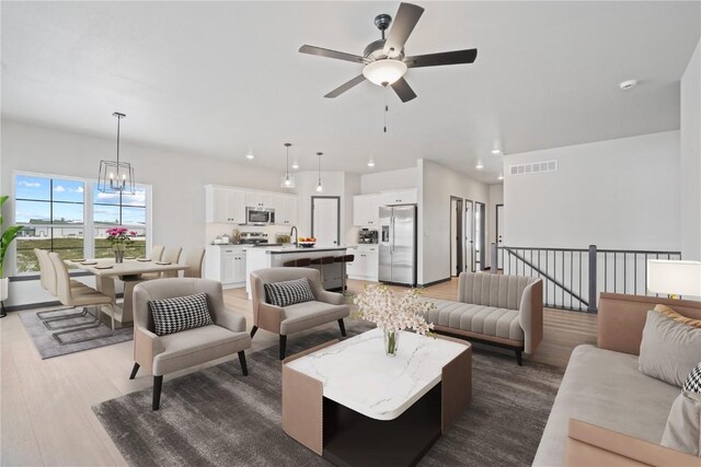 5017 Bluestem St SW, Kalona, IA 52247 - living area with a ceiling fan, light wood-style flooring, recessed lighting, and a chandelier