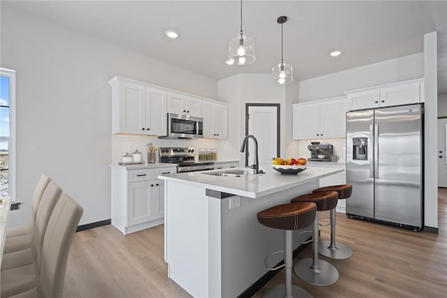 5017 Bluestem St SW, Kalona, IA 52247 - kitchen featuring appliances with stainless steel finishes, light wood-style flooring, a sink, a breakfast bar, and an island with sink