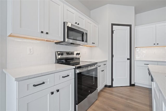 5017 Bluestem St SW, Kalona, IA 52247 - kitchen with stainless steel appliances, decorative backsplash, white cabinets, light wood-style flooring, and light stone countertops
