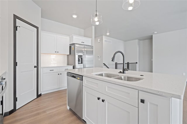 5017 Bluestem St SW, Kalona, IA 52247 - kitchen featuring stainless steel appliances, a sink, white cabinetry, decorative light fixtures, and light wood-type flooring