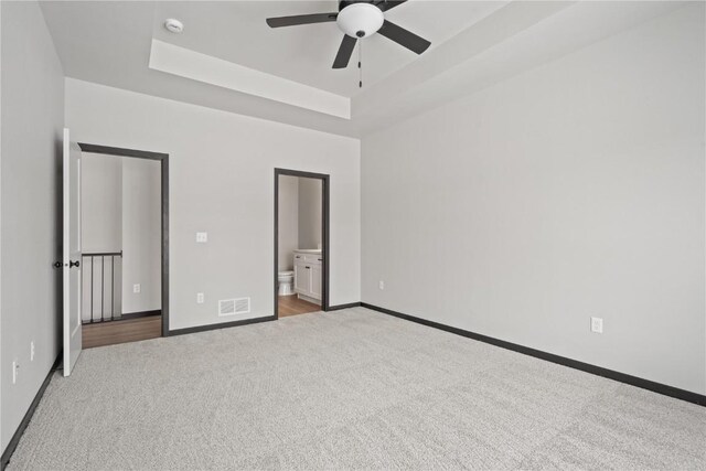 5017 Bluestem St SW, Kalona, IA 52247 - unfurnished bedroom with carpet floors, a tray ceiling, baseboards, and ensuite bathroom