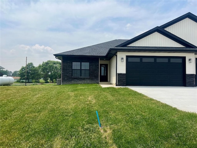 5021 Bluestem St SW, Kalona, IA 52247 - view of front of house with stone siding, a front lawn, driveway, a garage, and a shingled roof