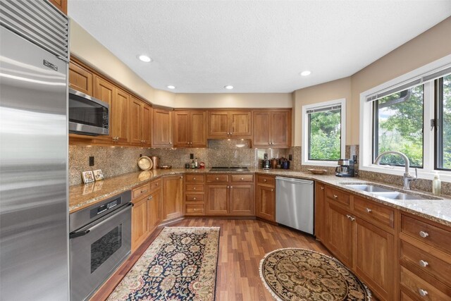 13 S View Dr NE, Iowa City, IA 52240 - kitchen featuring appliances with stainless steel finishes, a sink, brown cabinets, light wood-type flooring, and light stone countertops