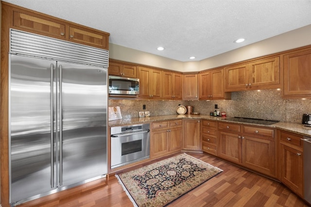 13 S View Dr NE, Iowa City, IA 52240 - kitchen with stainless steel appliances, light wood-style floors, brown cabinets, backsplash, and a textured ceiling