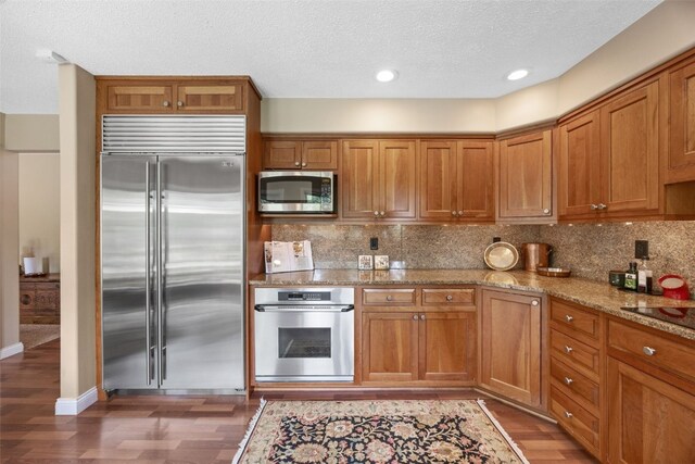 13 S View Dr NE, Iowa City, IA 52240 - kitchen featuring appliances with stainless steel finishes, brown cabinets, light wood-style flooring, decorative backsplash, and a textured ceiling