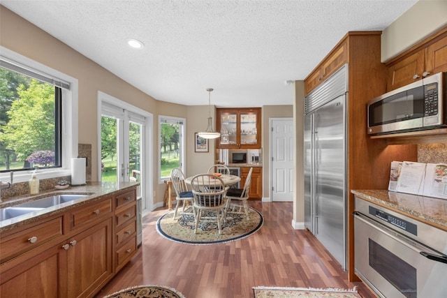13 S View Dr NE, Iowa City, IA 52240 - kitchen featuring appliances with stainless steel finishes, brown cabinets, wood finished floors, a sink, and a textured ceiling