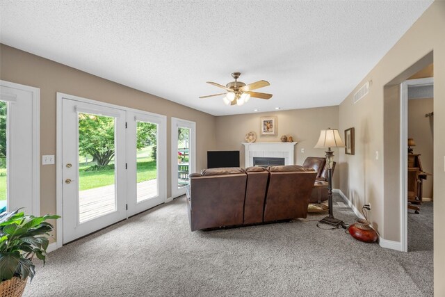 13 S View Dr NE, Iowa City, IA 52240 - carpeted living room featuring a ceiling fan, a tiled fireplace, baseboards, and a textured ceiling