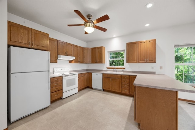 3017 Peaceful Dr, Riverside, IA 52327 - kitchen with white appliances, under cabinet range hood, a peninsula, a sink, and brown cabinetry