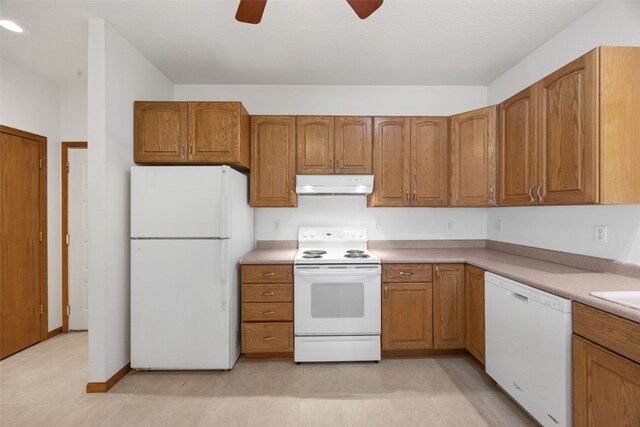 3017 Peaceful Dr, Riverside, IA 52327 - kitchen with white appliances, under cabinet range hood, brown cabinetry, and a ceiling fan