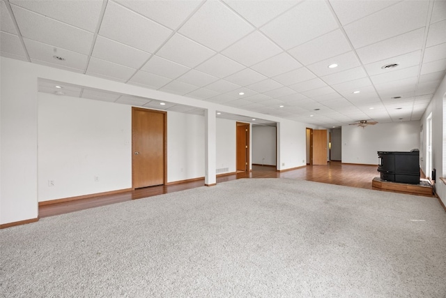 3017 Peaceful Dr, Riverside, IA 52327 - below grade area featuring a wood stove, carpet floors, a paneled ceiling, baseboards, and recessed lighting