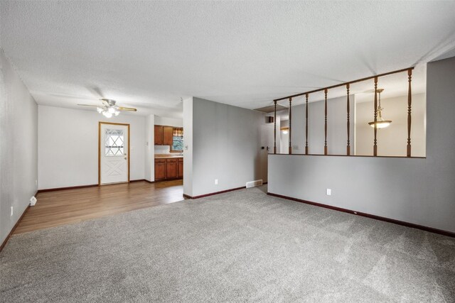 17 C Ave, Newhall, IA 52315 - unfurnished living room with carpet floors, a textured ceiling, ceiling fan, and baseboards