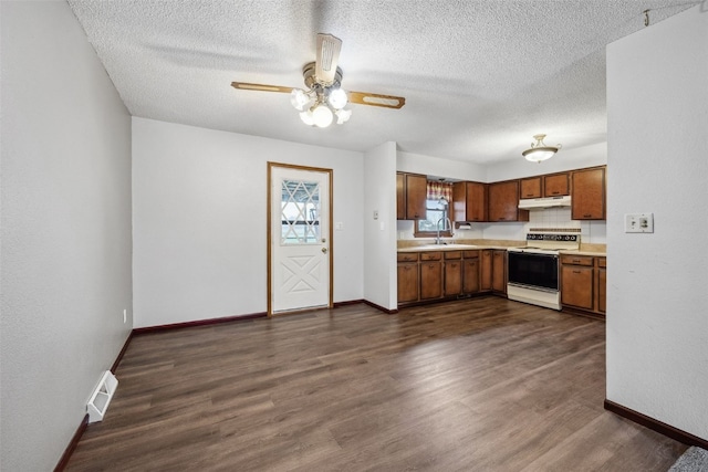 17 C Ave, Newhall, IA 52315 - kitchen featuring white range with electric cooktop, under cabinet range hood, light countertops, baseboards, and a textured ceiling