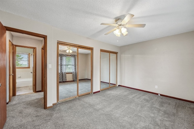 17 C Ave, Newhall, IA 52315 - unfurnished bedroom with multiple closets, carpet flooring, a textured ceiling, baseboards, and ceiling fan