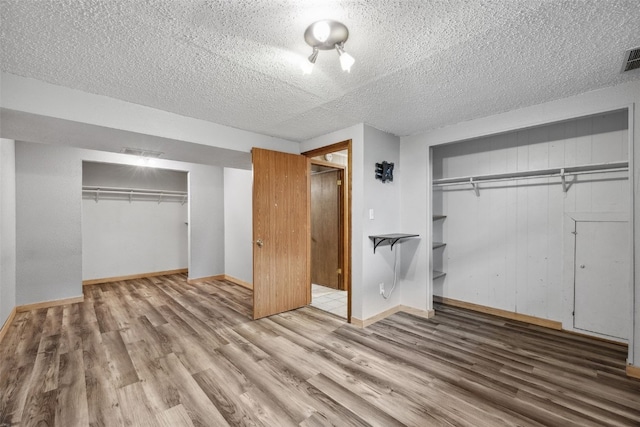 17 C Ave, Newhall, IA 52315 - unfurnished bedroom featuring wood finished floors, a textured ceiling, a closet, and baseboards