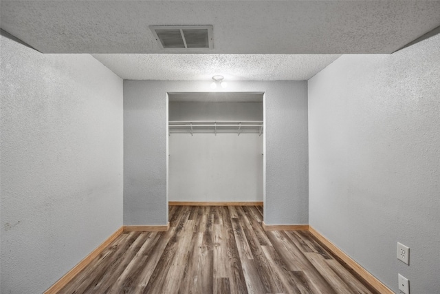 17 C Ave, Newhall, IA 52315 - unfurnished bedroom featuring baseboards, wood finished floors, a closet, a textured wall, and a textured ceiling