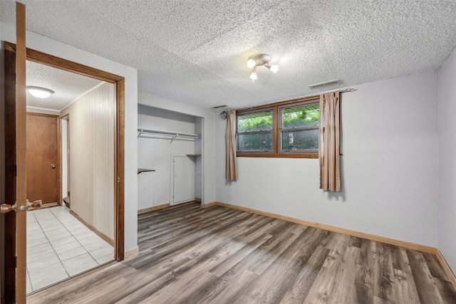 17 C Ave, Newhall, IA 52315 - unfurnished bedroom featuring light wood finished floors, a closet, baseboards, and a textured ceiling