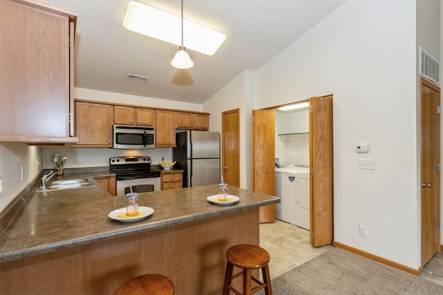 1080 Rachael St Unit 304, North Liberty, IA 52317 - kitchen featuring appliances with stainless steel finishes, washing machine and clothes dryer, a sink, vaulted ceiling, and dark countertops