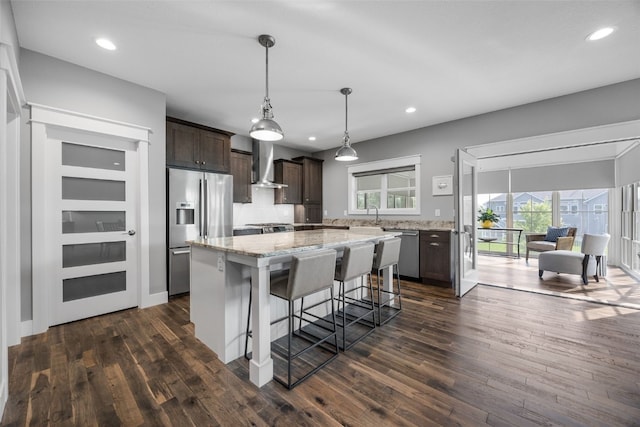 6318 Rapids Ridge Rd NE, Cedar Rapids, IA 52411 - kitchen with stainless steel appliances, wall chimney exhaust hood, dark brown cabinets, a center island, and dark wood-style flooring