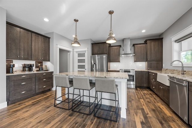 6318 Rapids Ridge Rd NE, Cedar Rapids, IA 52411 - kitchen featuring appliances with stainless steel finishes, wall chimney exhaust hood, dark brown cabinets, dark wood-type flooring, and a kitchen island