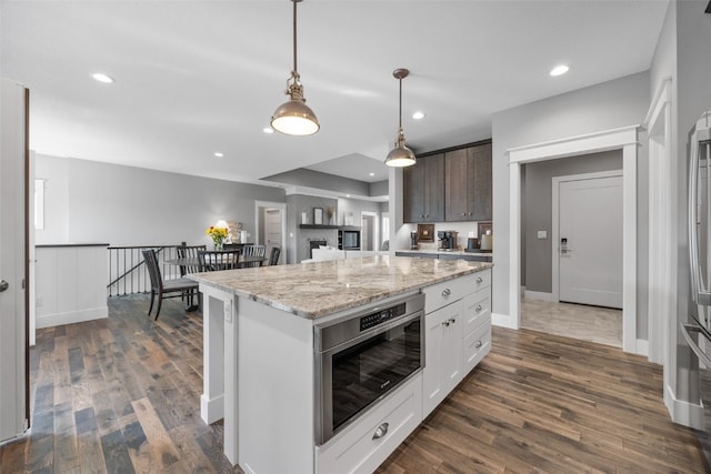 6318 Rapids Ridge Rd NE, Cedar Rapids, IA 52411 - kitchen with dark wood finished floors, hanging light fixtures, light stone countertops, recessed lighting, and a kitchen island